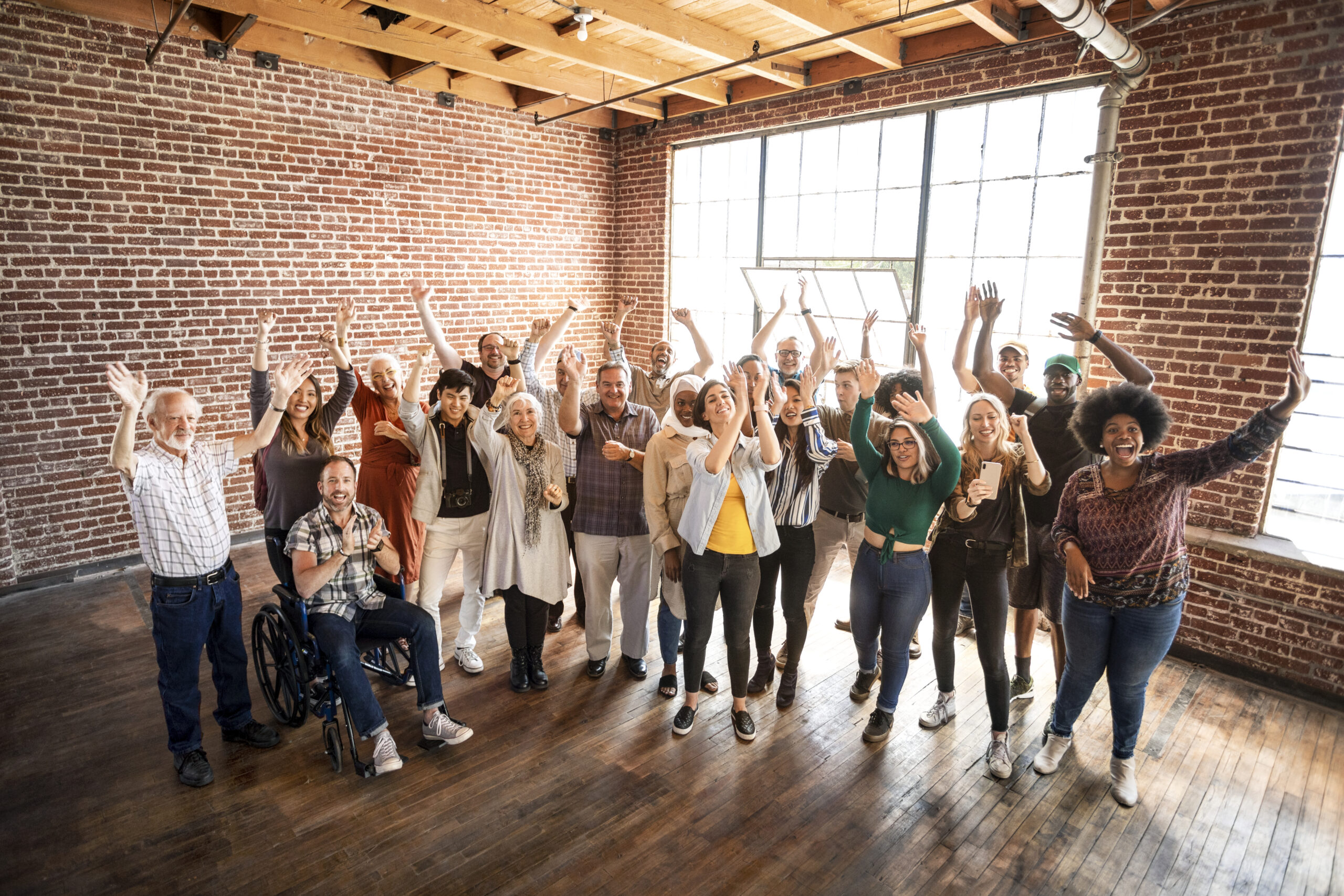 A diverse group of people raising their hands in celebration